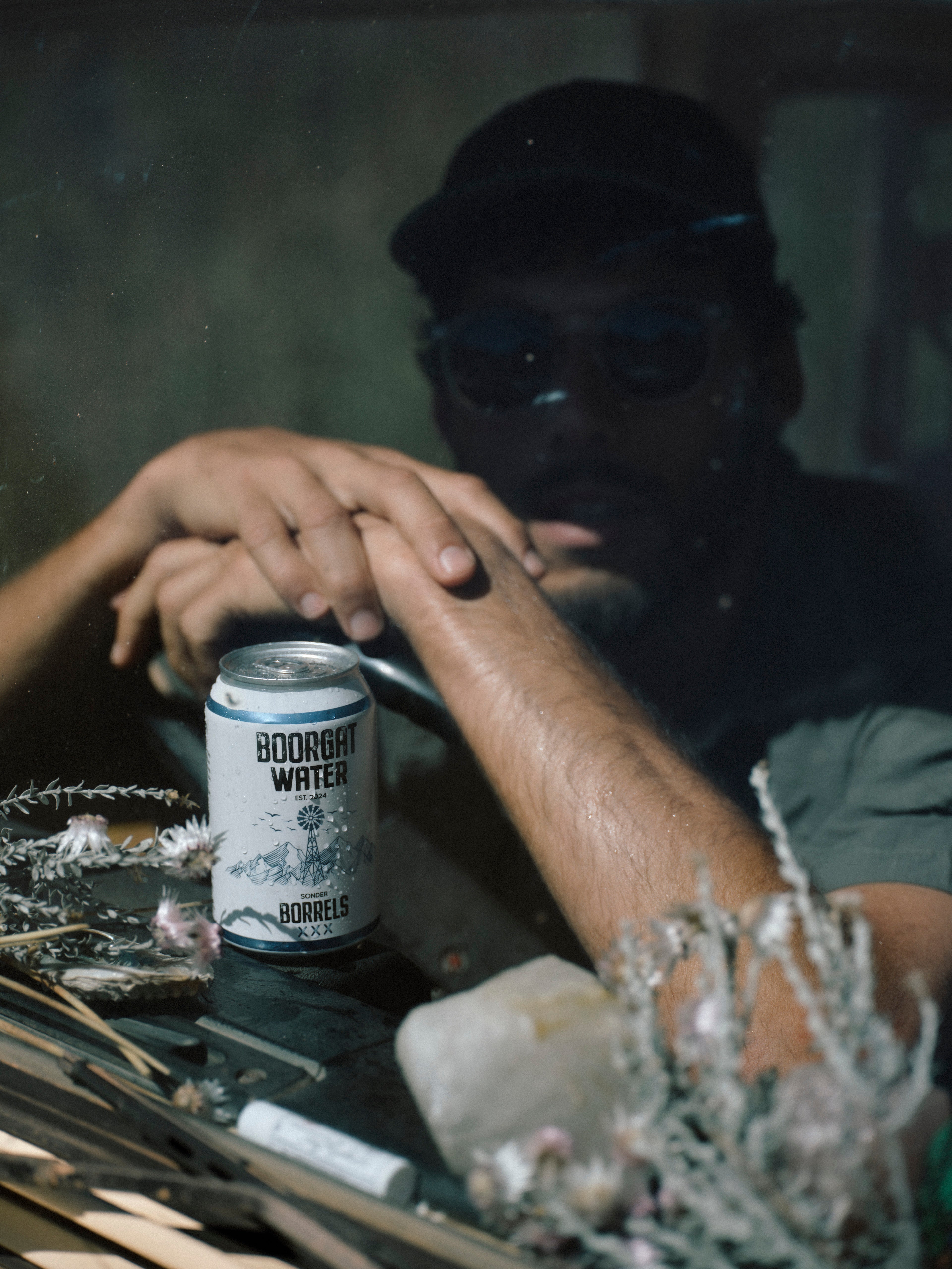 Person holding a can of 'Boorgat Water' with a dark background